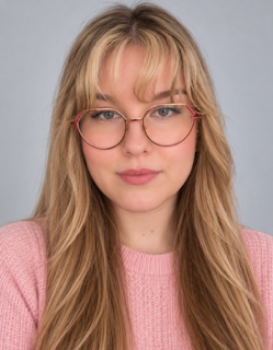 Headshot of a woman with blonde hair, bangs, and rose gold glasses, wearing a pink sweater.